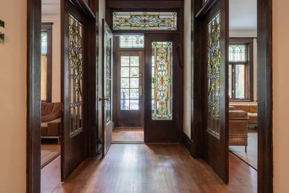 Hardwood floors, a hallway with ornate stain glass windows in wooden doors.