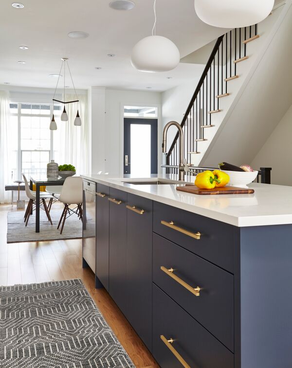 blue kitchen island with brass pulls and white top, runner in front, looking into open concept front dining room