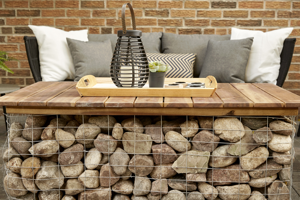 A stack of rocks in a steel wire net that is transformed into a rustic backyard table