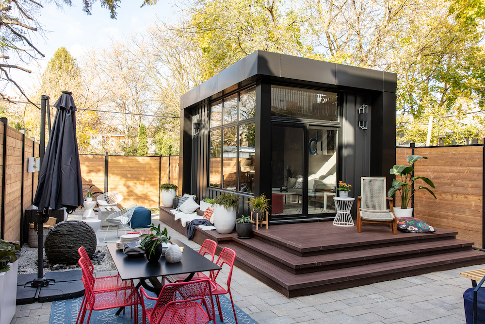 backyard with wood fence, black studio structure and outdoor dining space