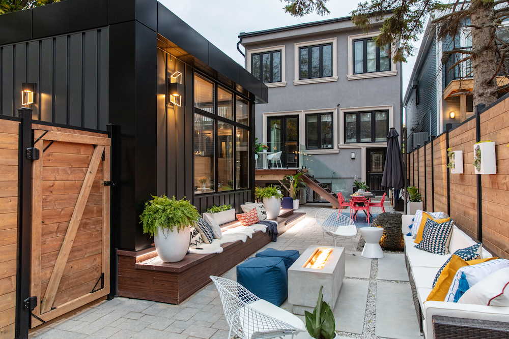 urban-glam backyard with black studio structure, outdoor lounge and outdoor dining area in distance