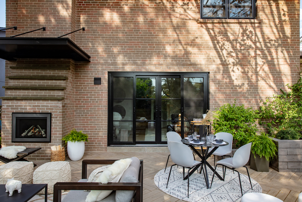 renovated outdoor patio with dining space, gas fireplace and new black-framed glass doors