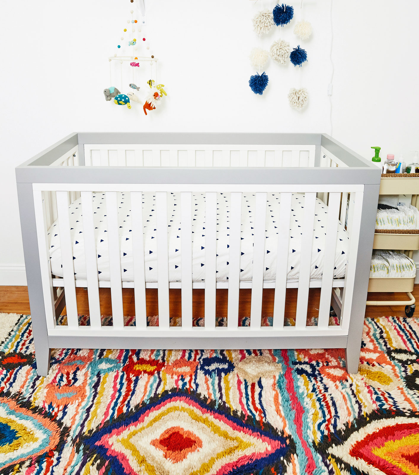white and grey crib in baby's nursery with morracan rug on floor