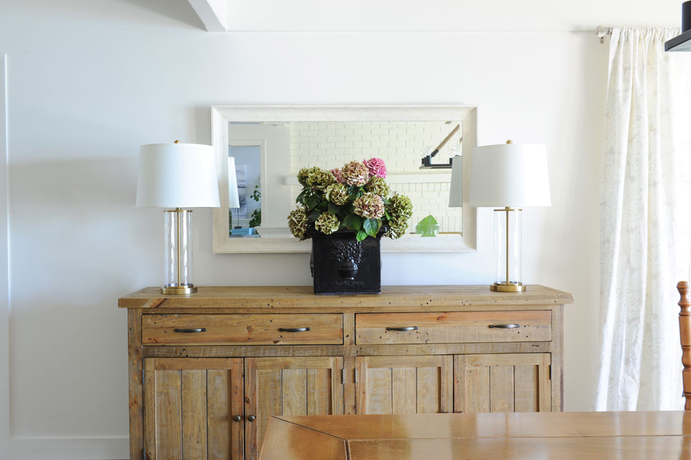 dining room wood buffet with two lamps, mirror and hydrangea