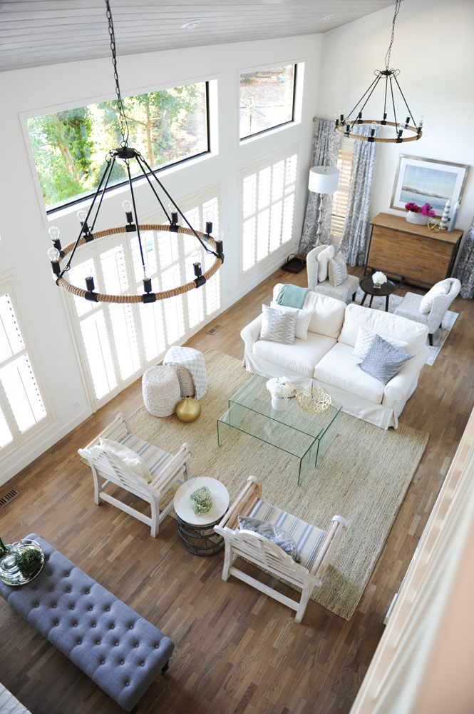 overhead shot of double vaulted living room with grey tufted long stool in bottom left