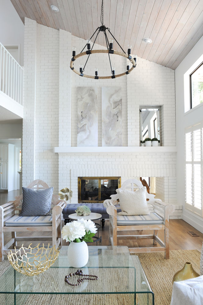 double vaulted white brick living room facing fireplace with clear nesting tables in foreground