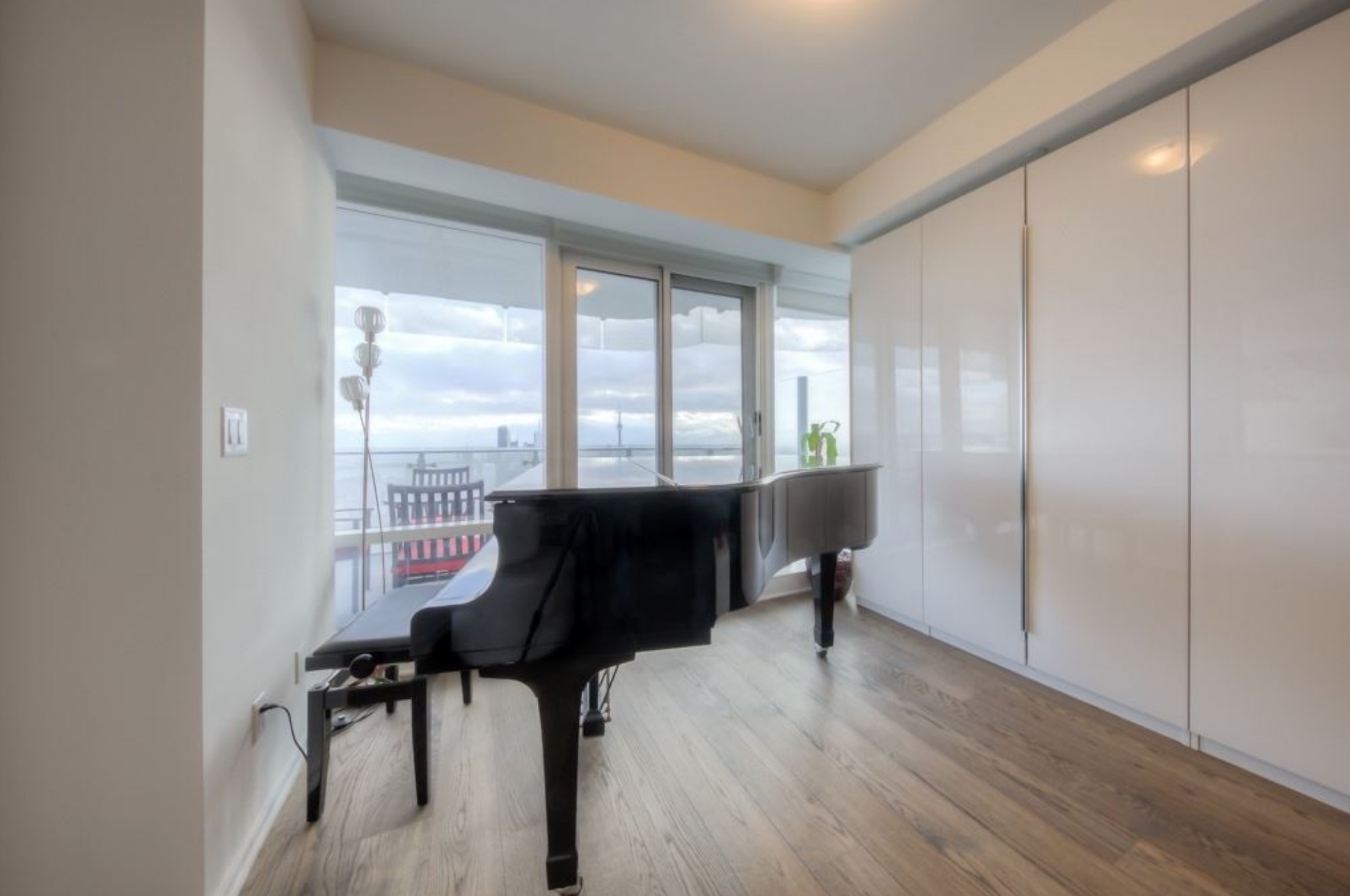 A baby grand piano situated in front of floor-to-ceiling windows in the living room space