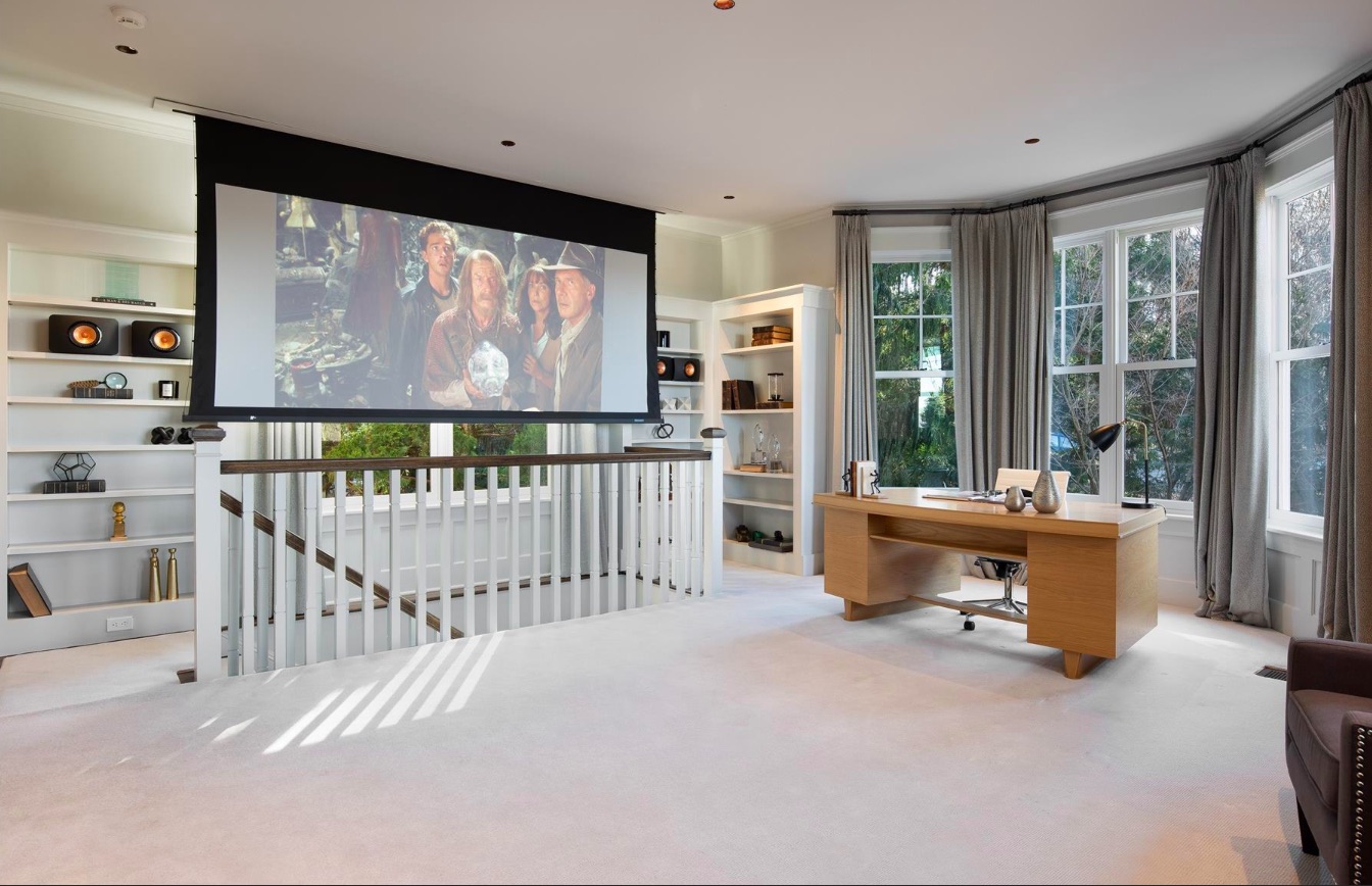 A spacious home office with large bank of windows and retractable screen for watching movies
