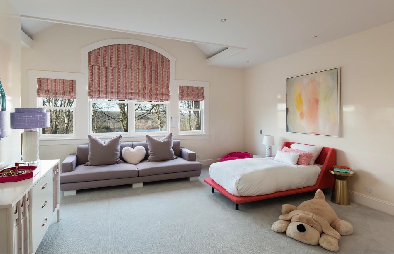 A child's bedroom with a red bed, grey furniture and white storage space