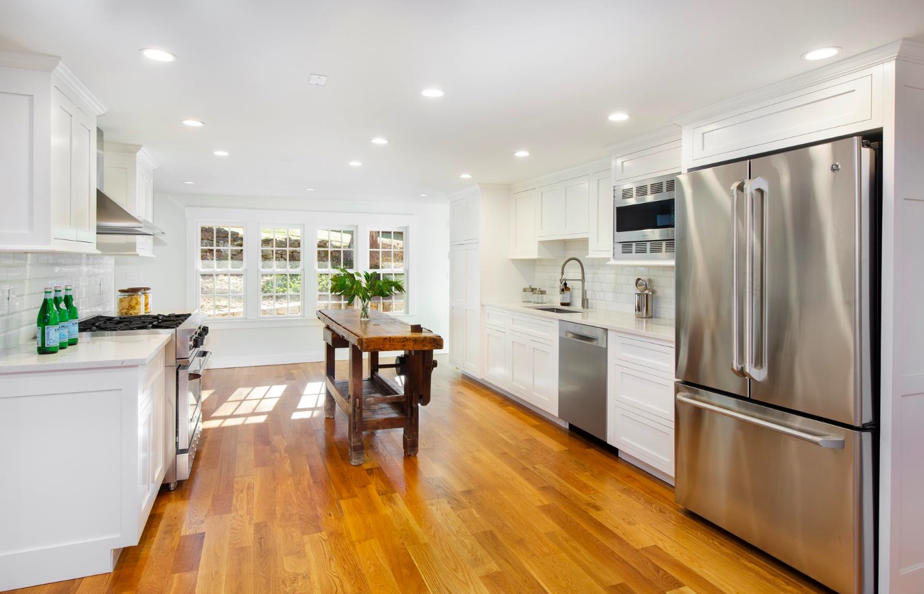 A sleek, spacious kitchen with hardwood flooring and a tiny island in the centre