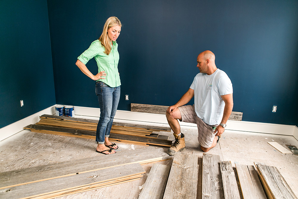 Bryan and Sarah Baeumler in a bare room with hardwood floor panels on the floor