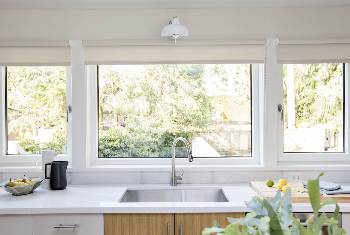 3 large windows in a kitchen looking into a yard