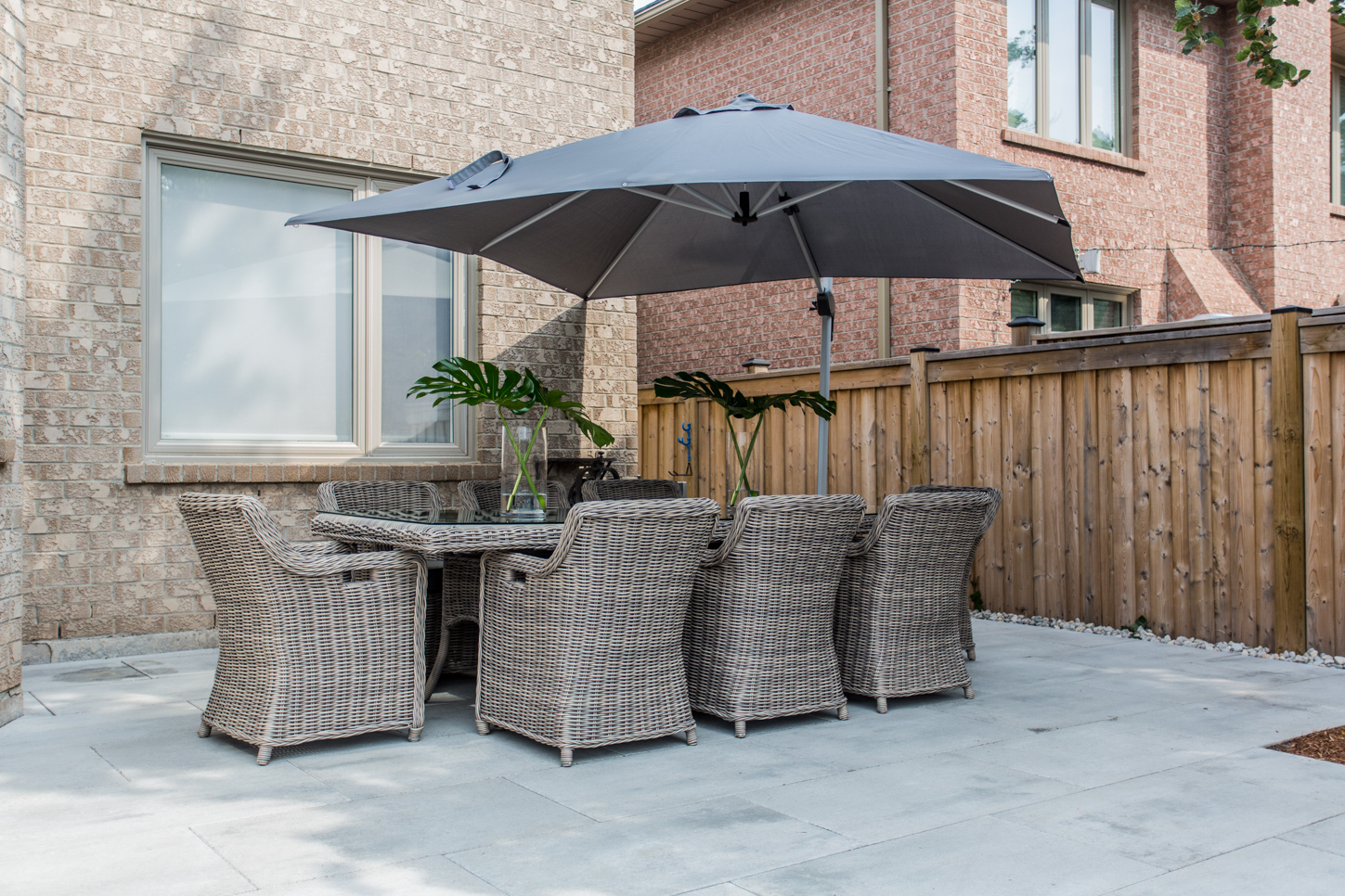 Backyard patio with wicker dining set under an umbrella