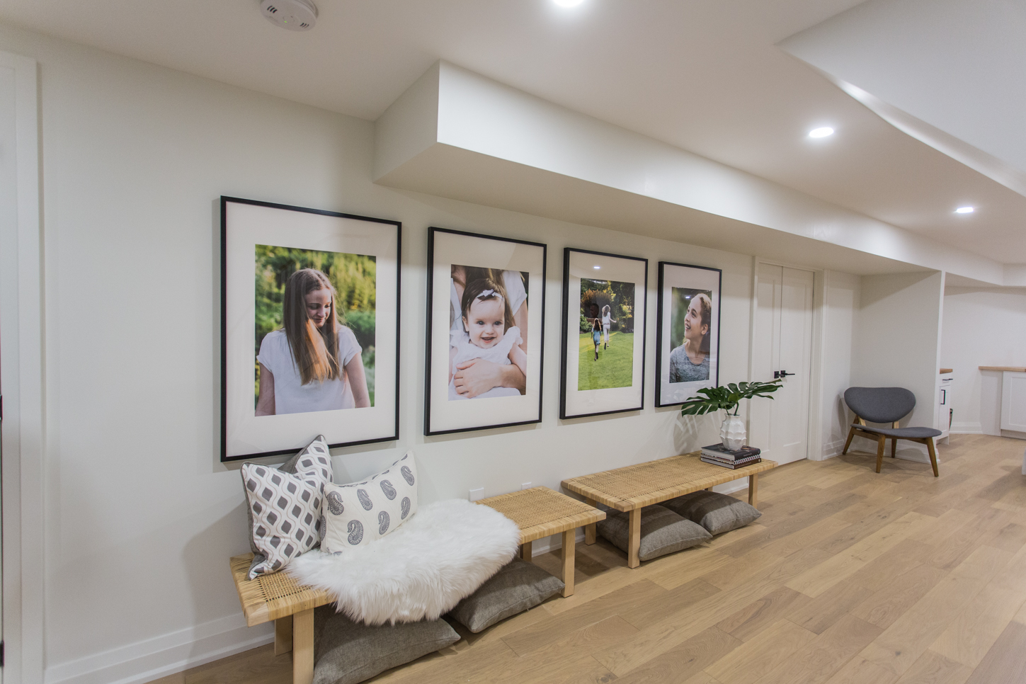Large family photos on wall of basement hung over benches