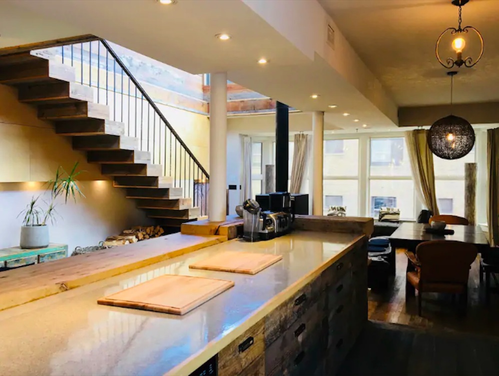 Rustic kitchen with large island and stairs off to the left-hand side