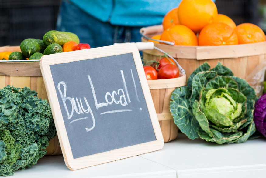 A small chalkboard sign at a farmer's market that reads Buy Local!