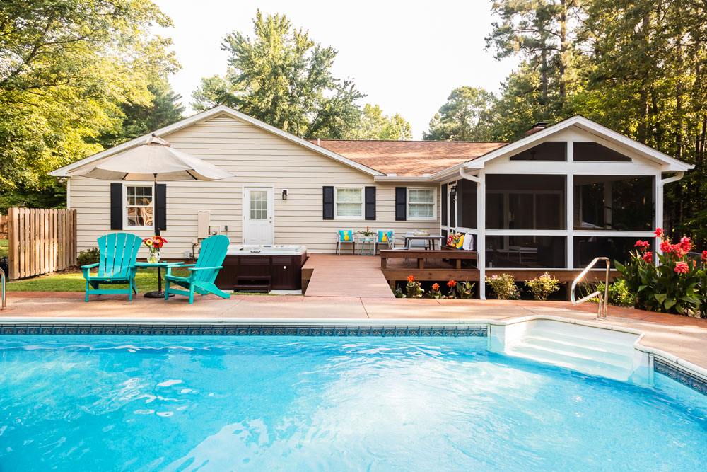 Renovated backyard with large pool, hot tub, and covered porch.