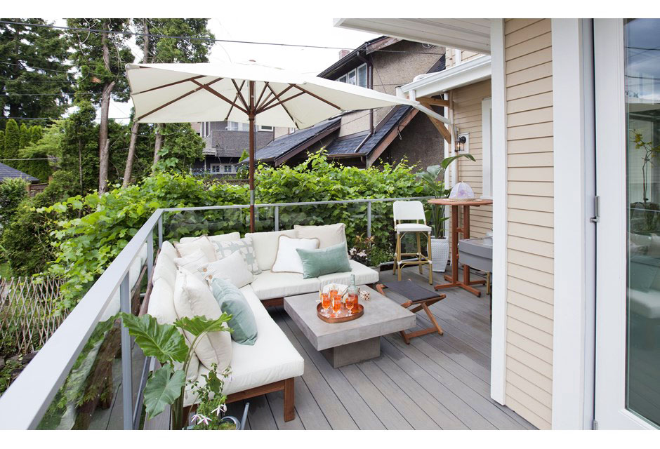 Gorgeous designed deck with small L-shaped sofa, umbrella and pillows.
