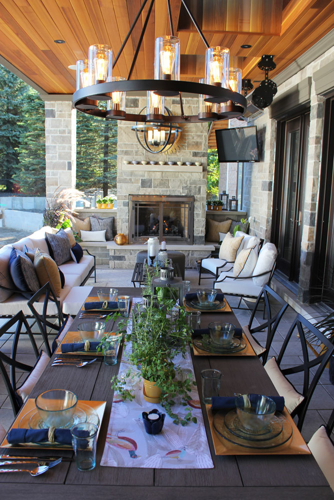 Dreamy covered outdoor space with built-in stone fireplace and dining room.
