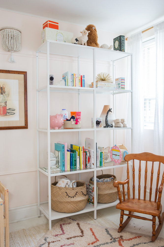 white toy shelves in girl's room beside little wooden rocking chair