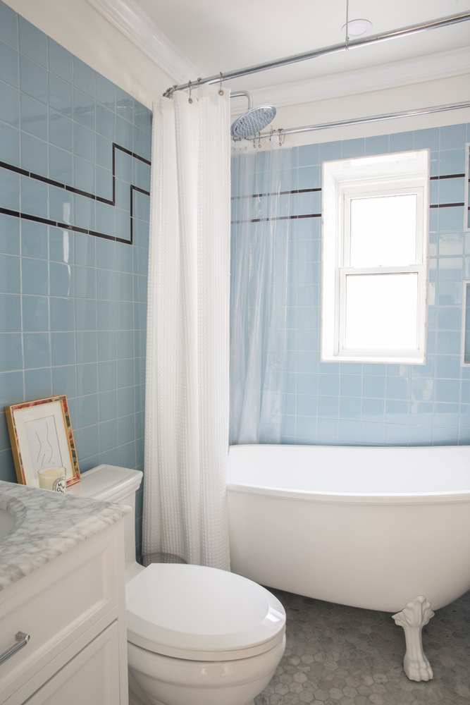 blue tile wall bathroom with black tile detail and white clawfoot tub