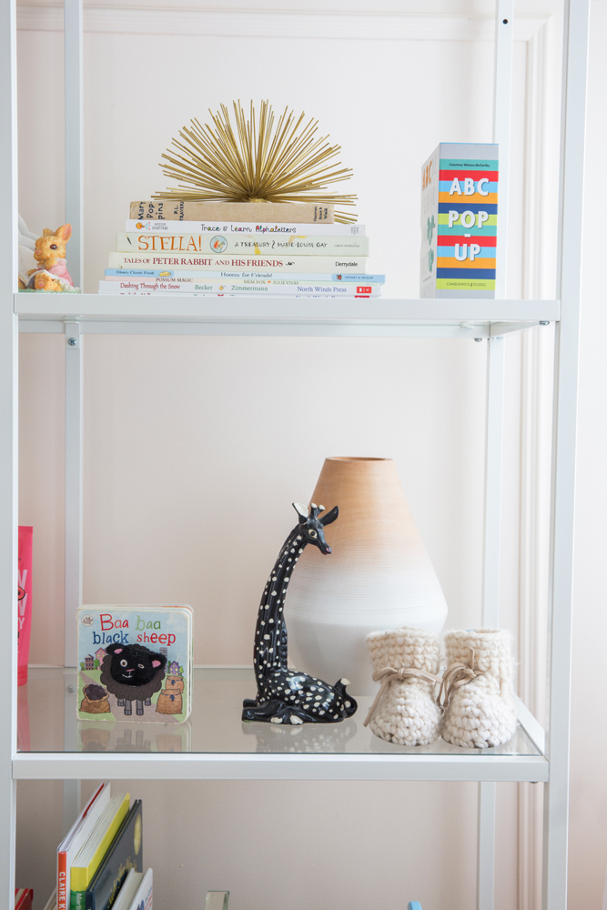 closeup of toy shelf with book, giraffe and nubby booties