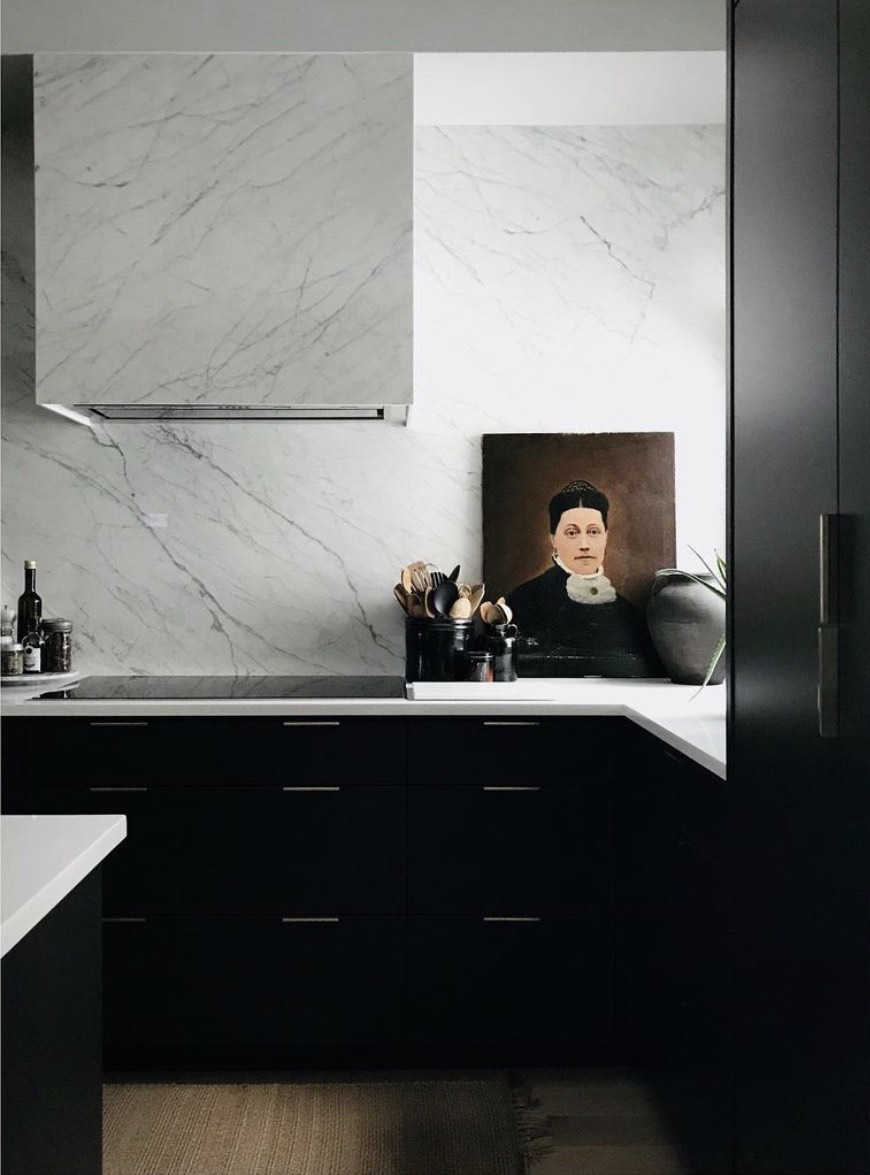 Contemporary marble and black kitchen with old portrait painting