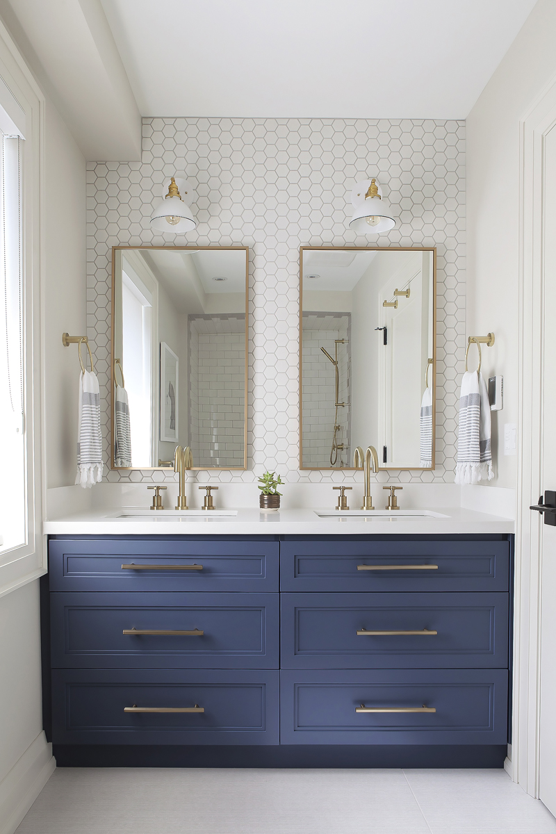 A grown-up kids' bathroom with deep blue cabinets and hexagonal backsplash tiles