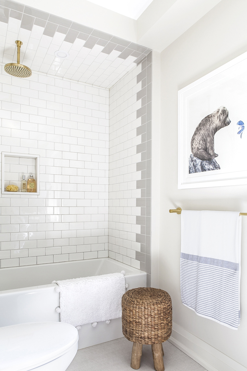 Newly renovated bathroom with white-and-grey tile work and brass shower head