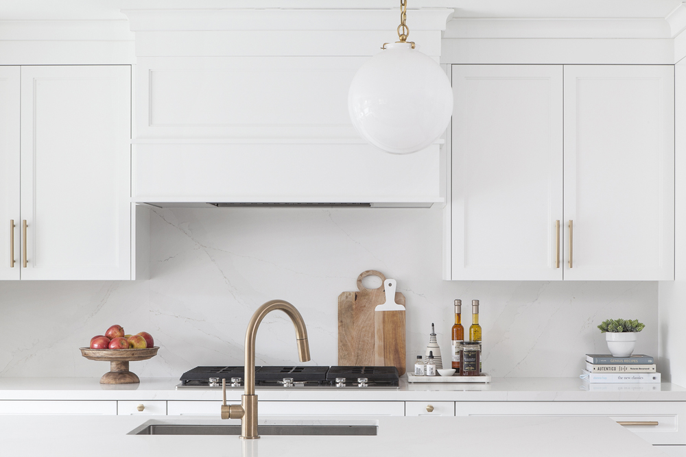 Sleek kitchen in warm, neutral colours and featuring brass hardware