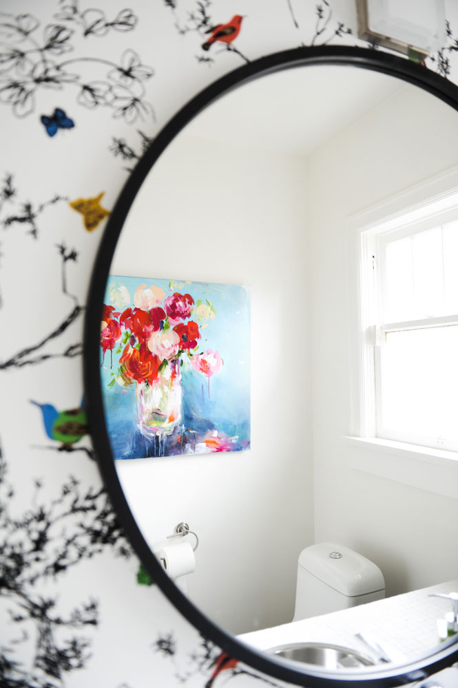 Round bathroom mirror reflecting floral oil painting
