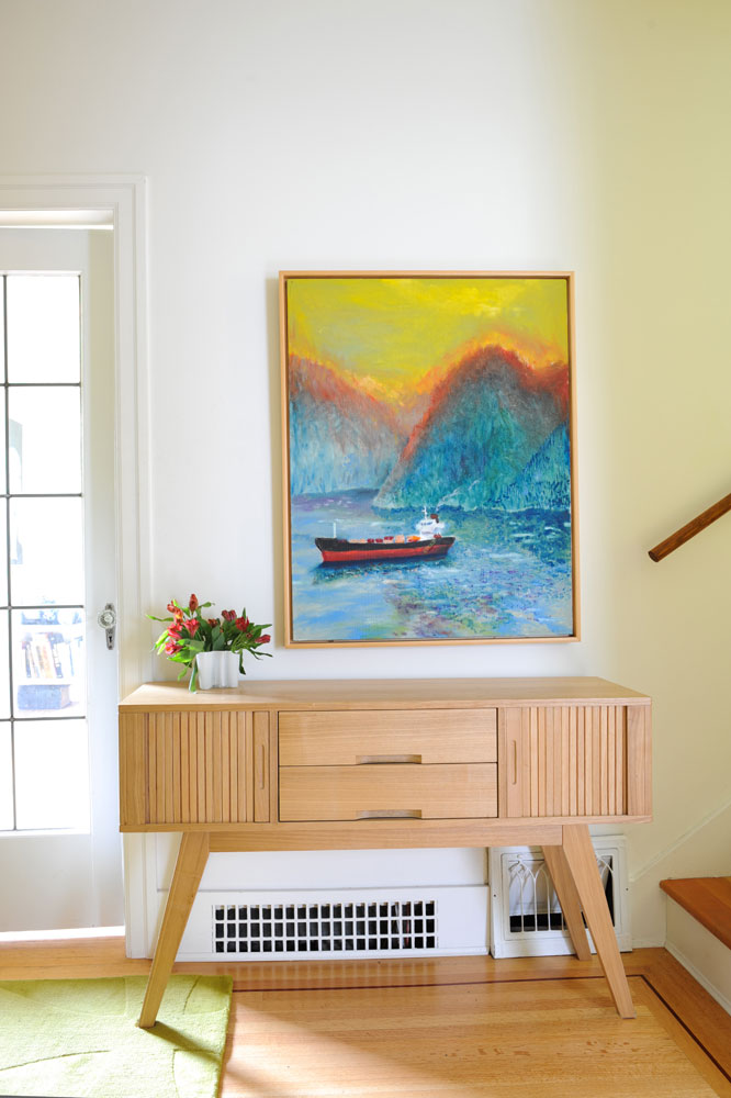 Ship painting over light wood console by stairs