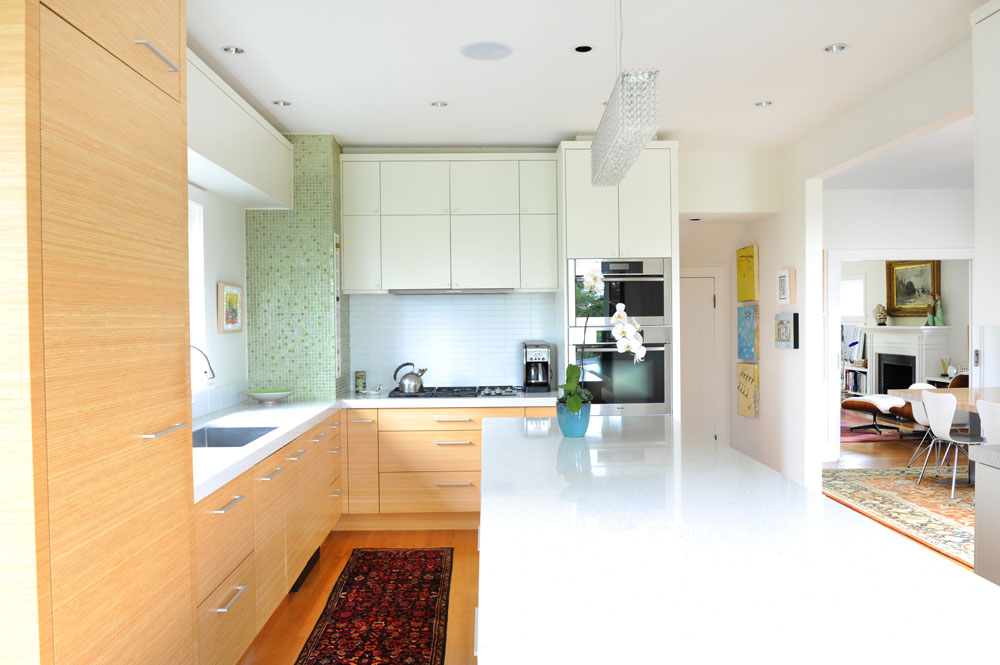 Kitchen with white top island, pale cabinets and green mosaic tiles