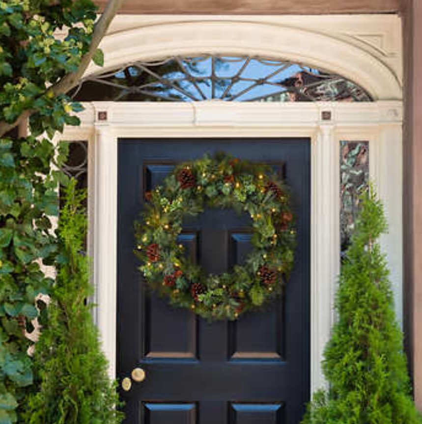 Black front door with festive wreath with lights