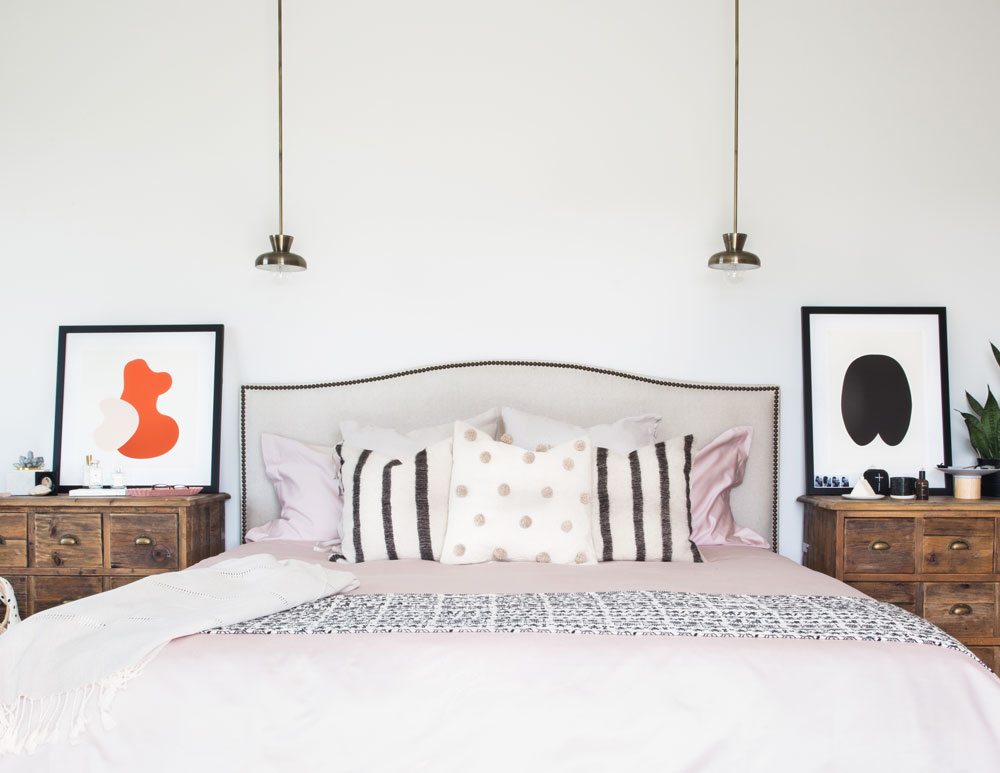 bed with orange and white bedside table artwork on left, black and white on right