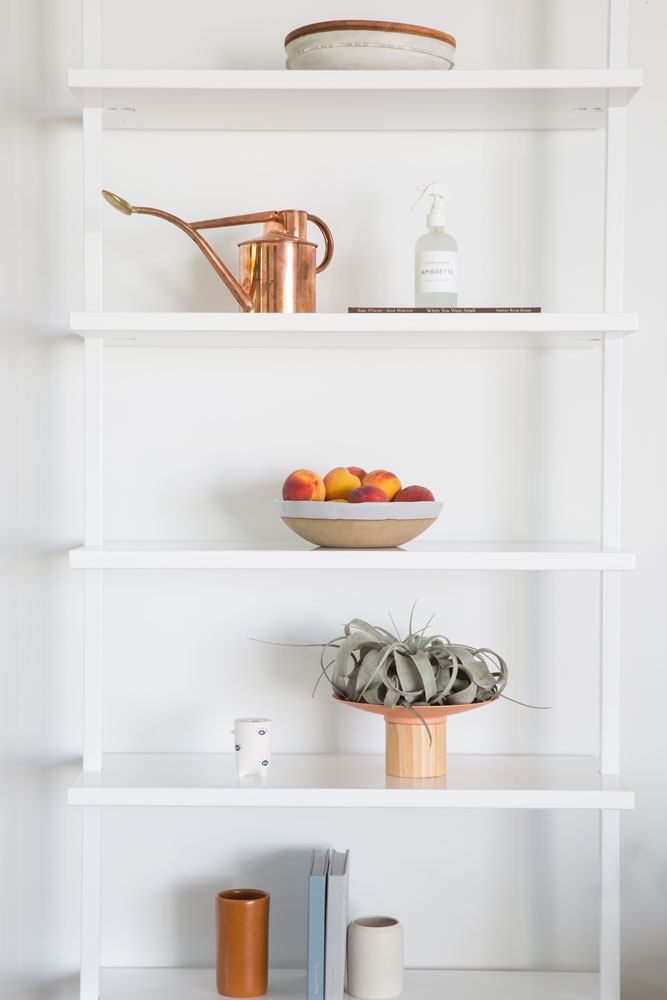 closeup of white shelves, one with bowl of peaches