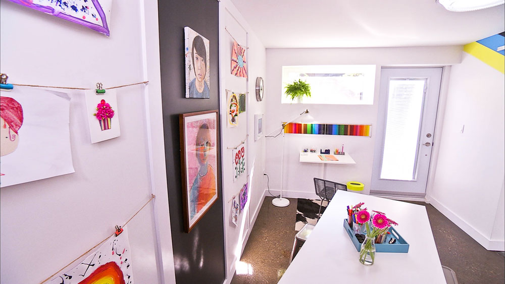 A clubhouse-style kids' crafts room with a desk and mounted artwork