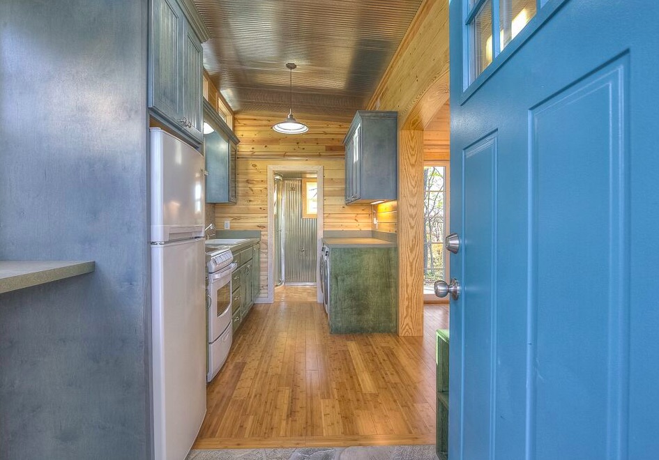 Renovated storage container kitchen with blue cabinetry and hardwood floors