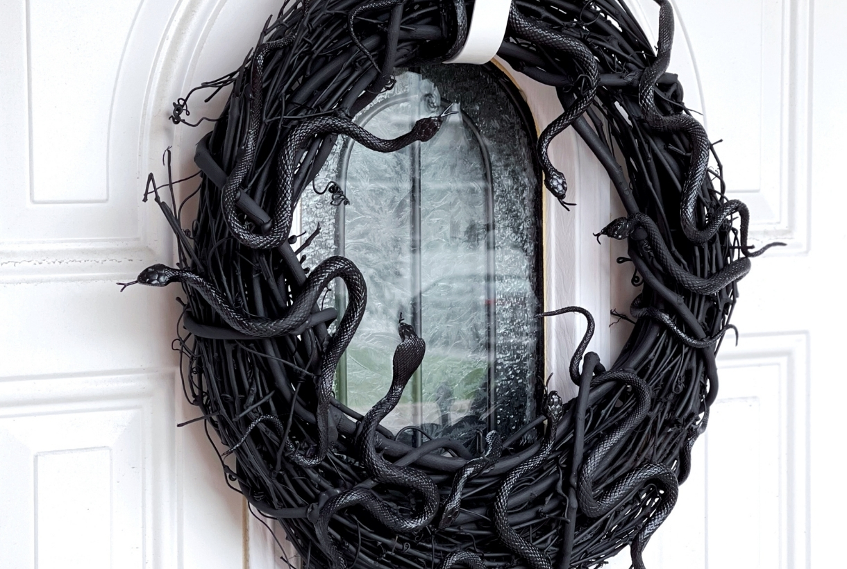 A sblack DIY snake Halloween wreath on a white door