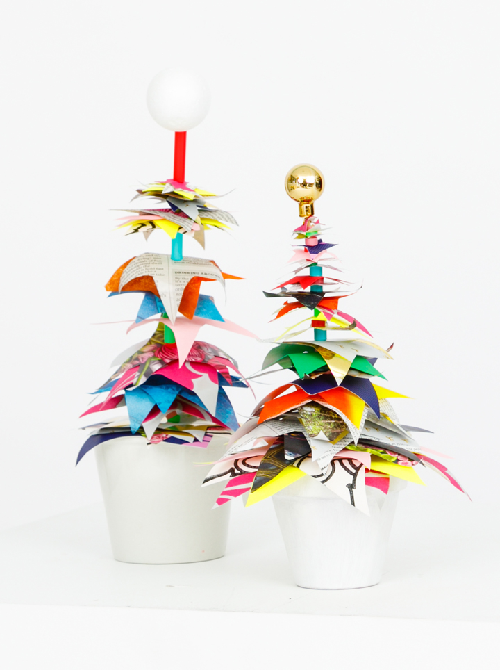 A white painted pot with recycled paper with stars as a holiday tree