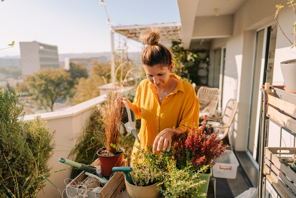 woman caring for plants on balcony