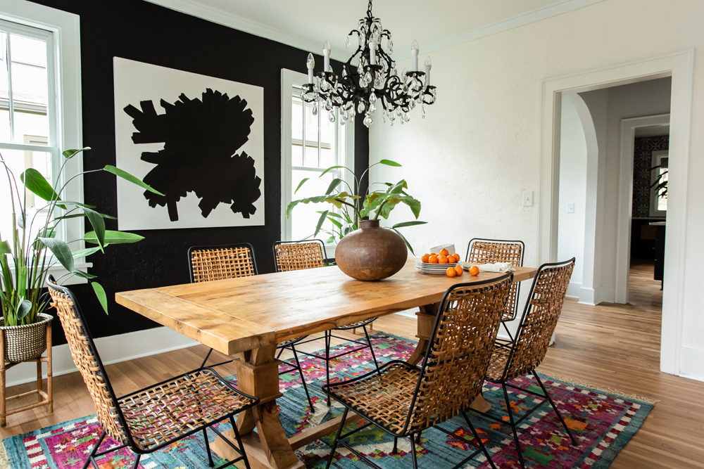 A bold renovated kitchen with elaborate chandelier, wicker chairs and patterned rug