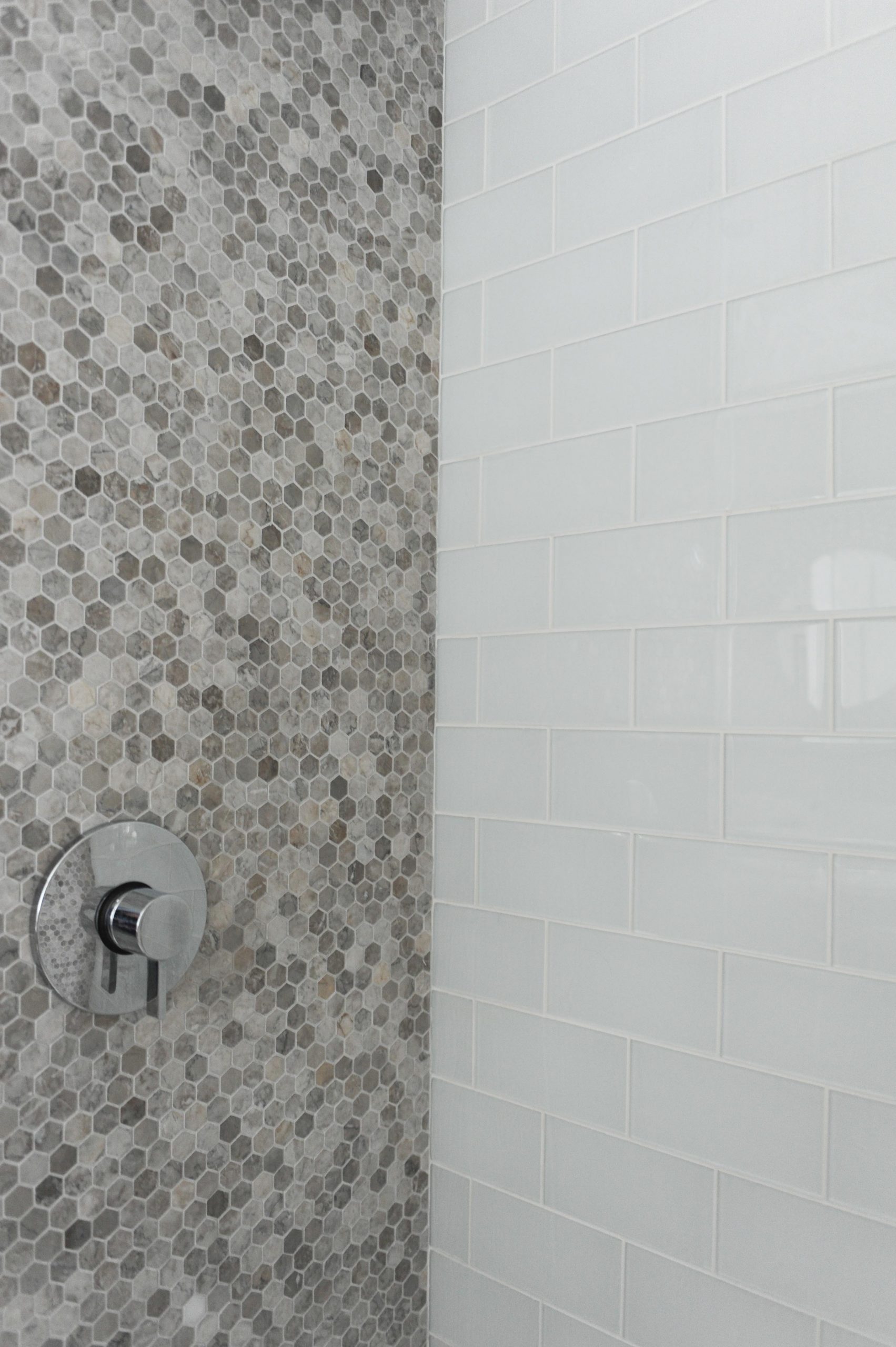 Shower wall clad in marble herringbone and white subway tiles.