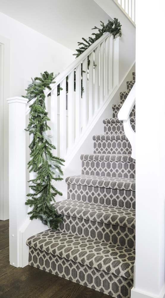 Staircase with fresh green garland and patterned rug