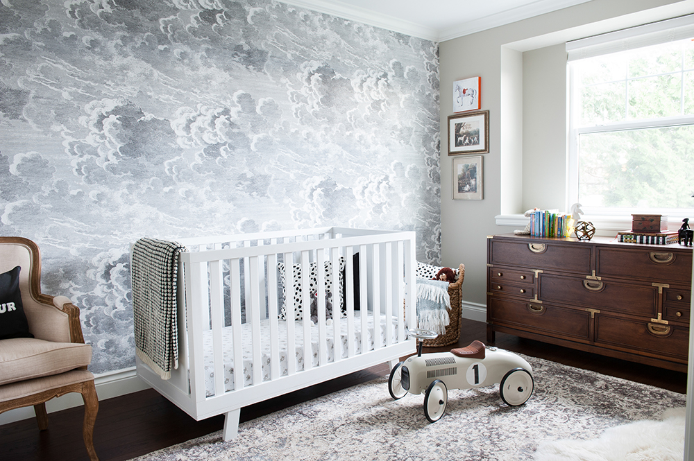 Whimsical nursery featuring cloud-patterned wallpaper.