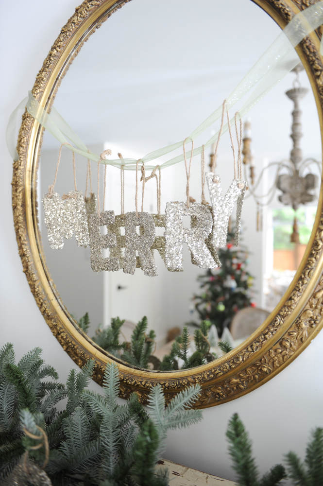 Glitter holiday letters strung onto round gold-framed mirror.