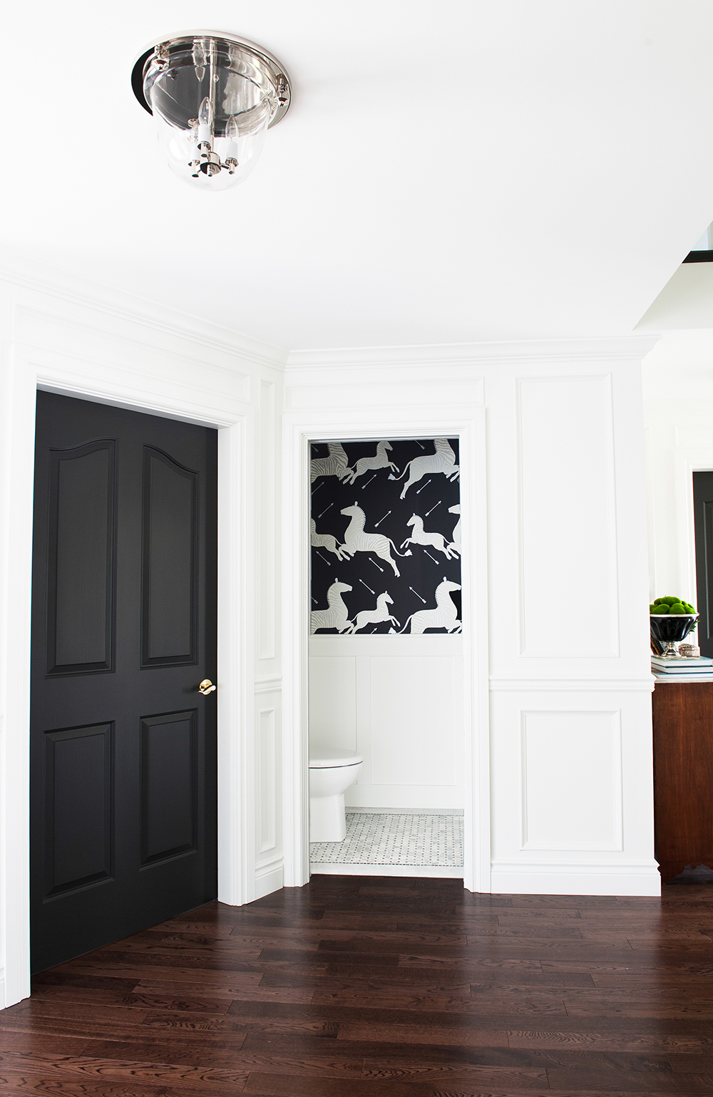 A bold black powder room with dramatic wallpaper.