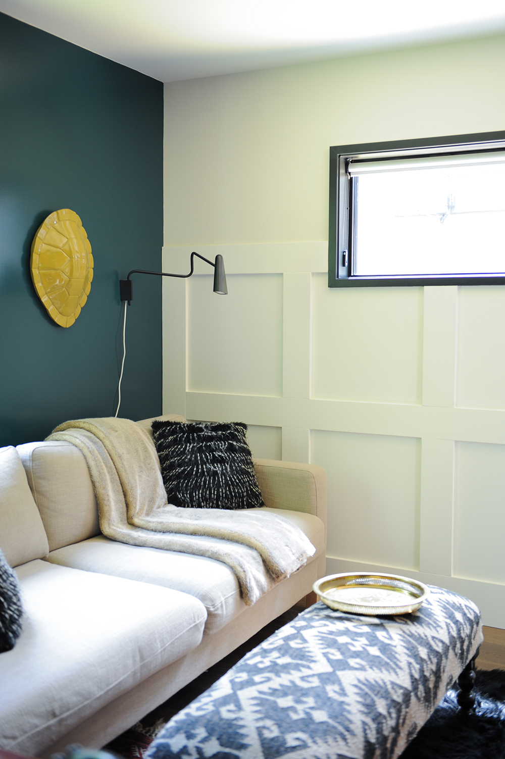 corner with dark green back wall and white wainscotting and sofa