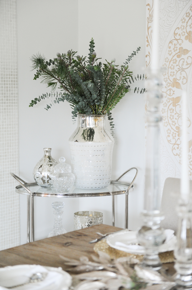 Bunch of greenery in silvery vase in corner of dining area