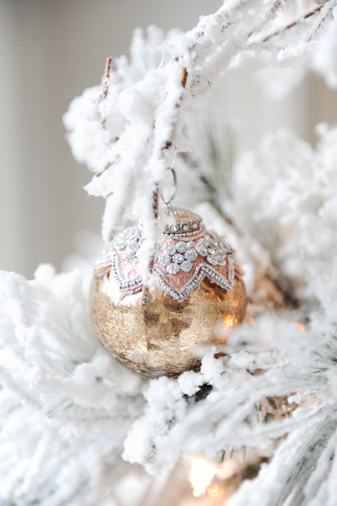 Close up of tree ornament amongst snow flocked branches